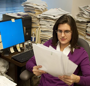 Женщина в офисе с кипой бумаг